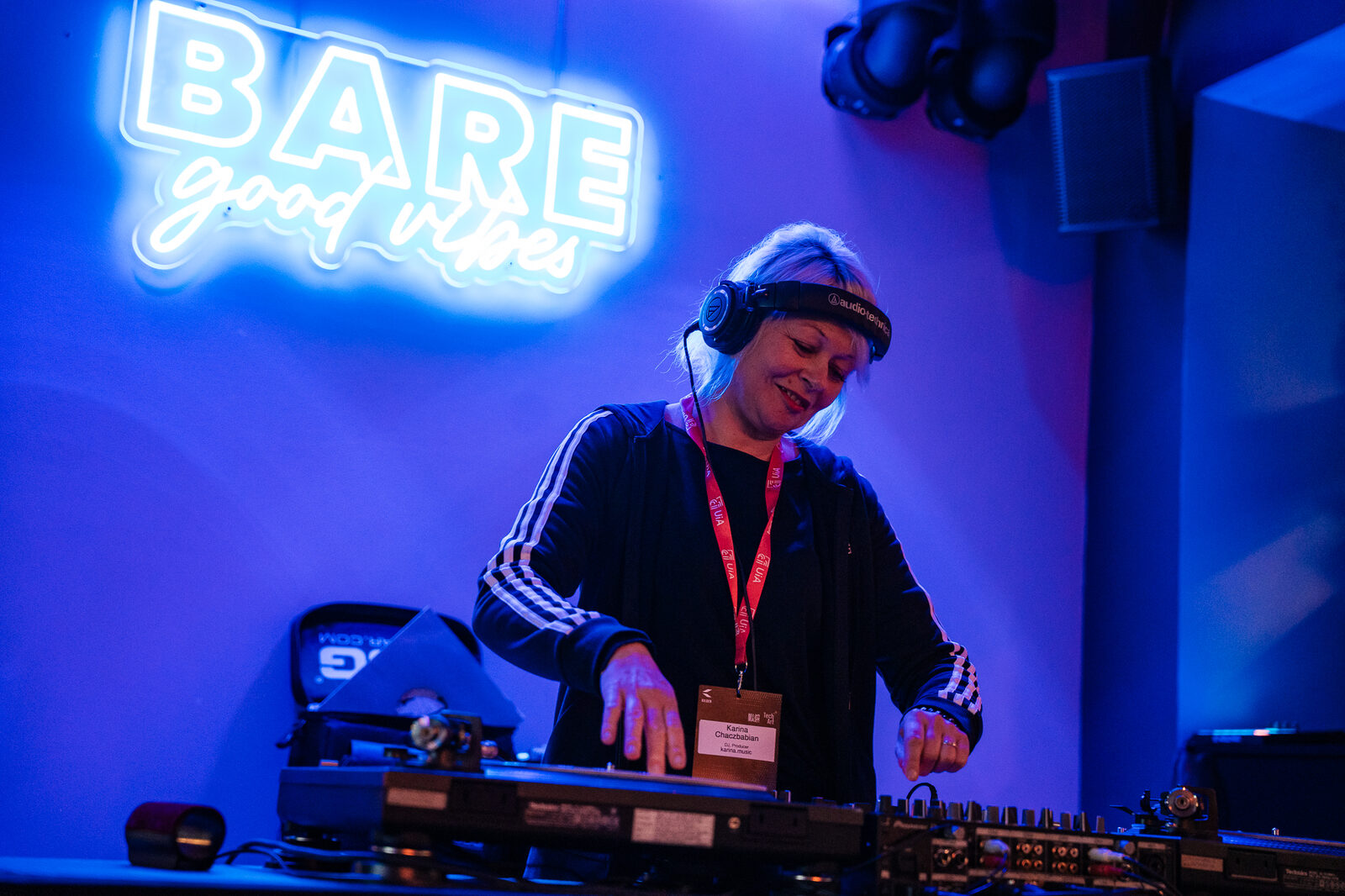 A DJ playing under a neon sign reading BARE